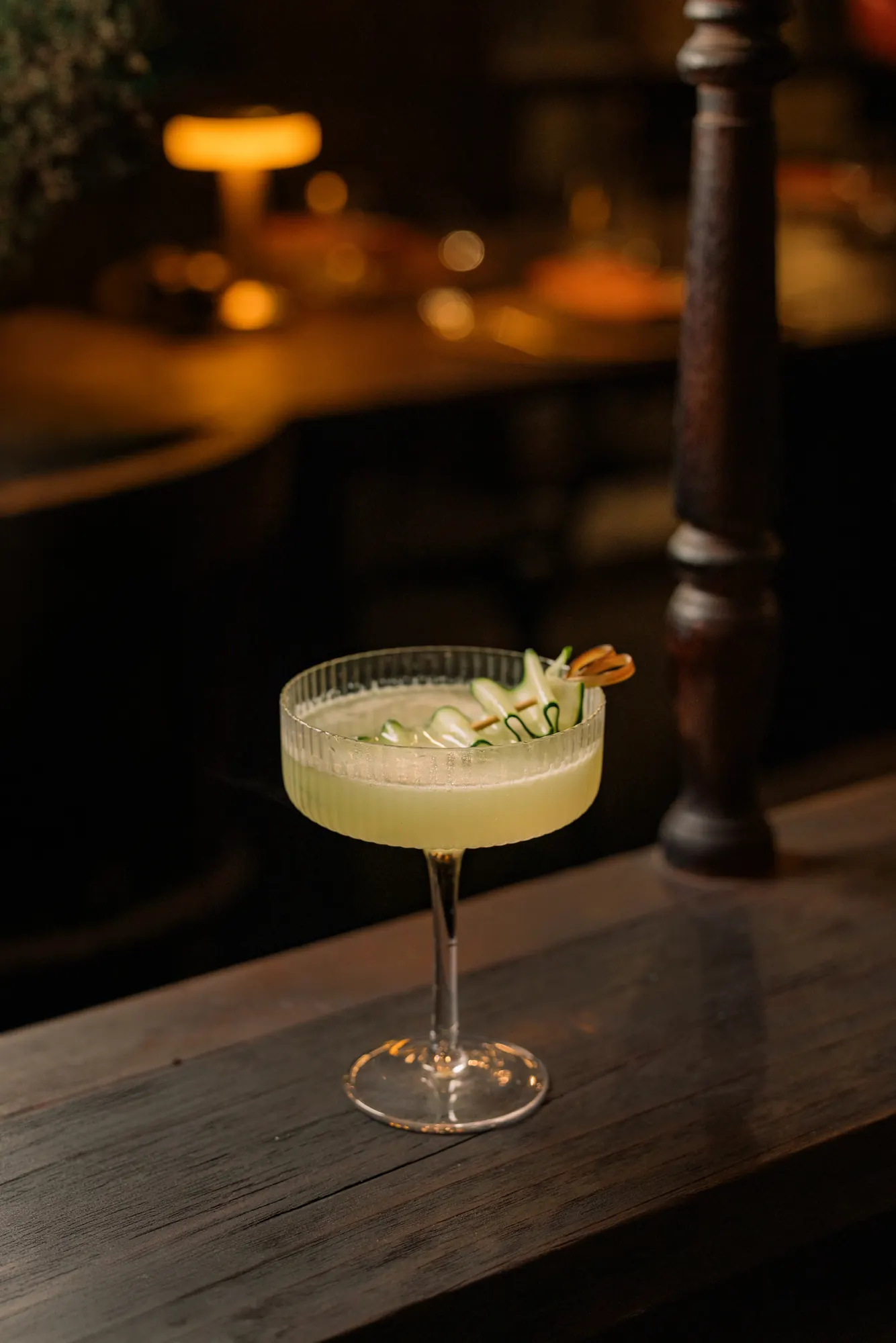 A pale yuzu cocktail in a coupe on the bar