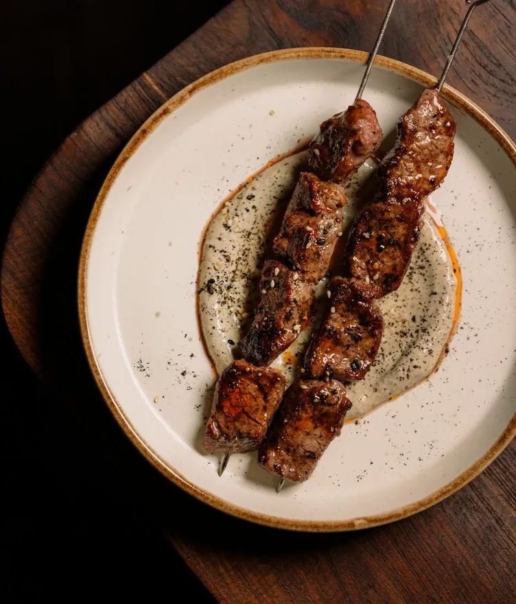 Two wagyu beef skewers on smoked onion aioli