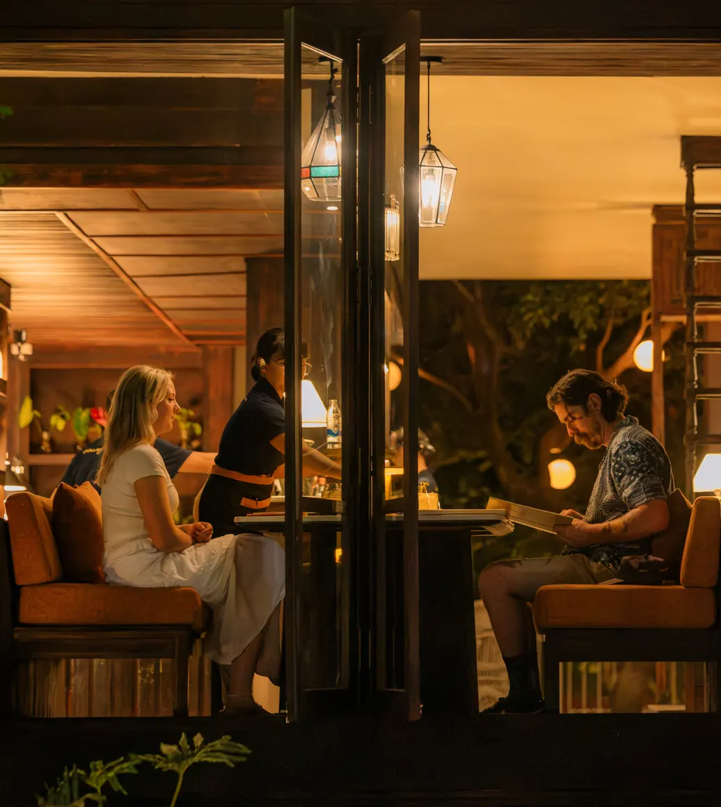 Guests dining at Hibana in the evening, seen through the open doors